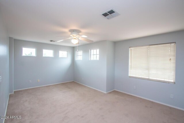 empty room with ceiling fan, plenty of natural light, and light carpet