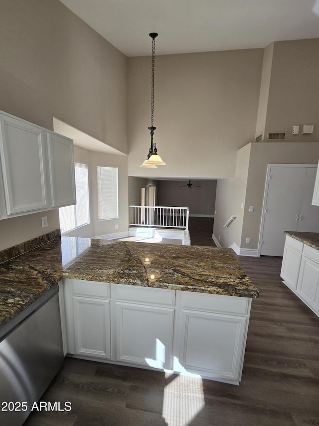 kitchen featuring white cabinetry, a towering ceiling, decorative light fixtures, and kitchen peninsula