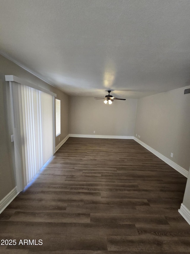 empty room with a textured ceiling, dark hardwood / wood-style floors, and ceiling fan