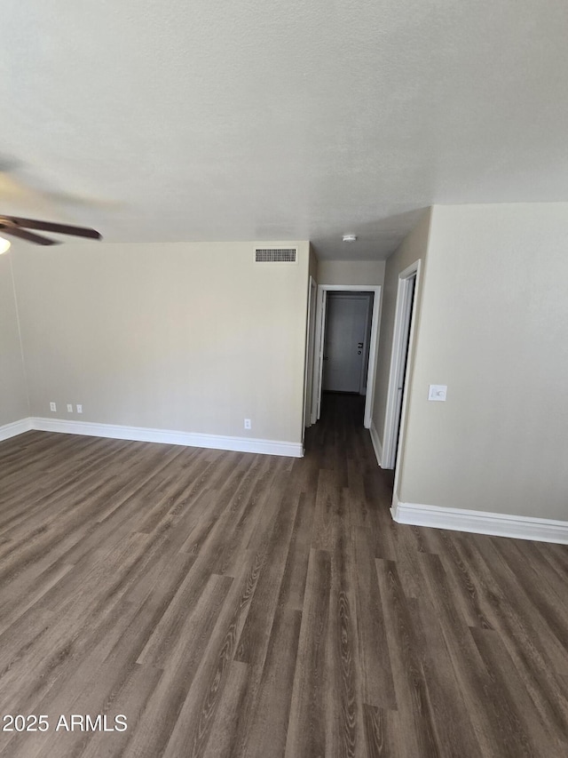 empty room featuring dark wood-type flooring, a textured ceiling, and ceiling fan