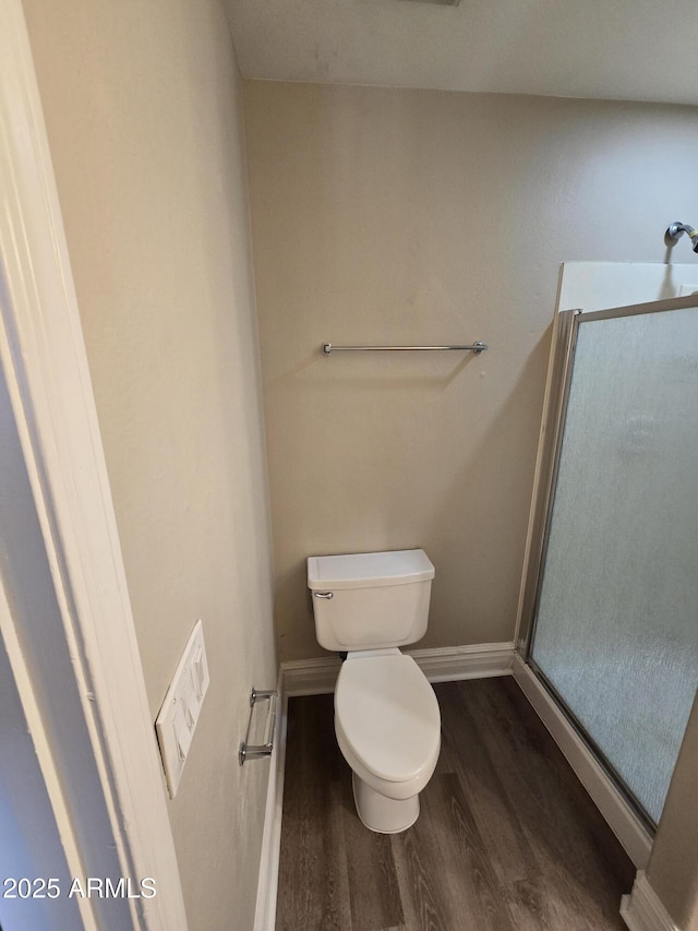 bathroom featuring toilet, a shower with shower door, and hardwood / wood-style floors