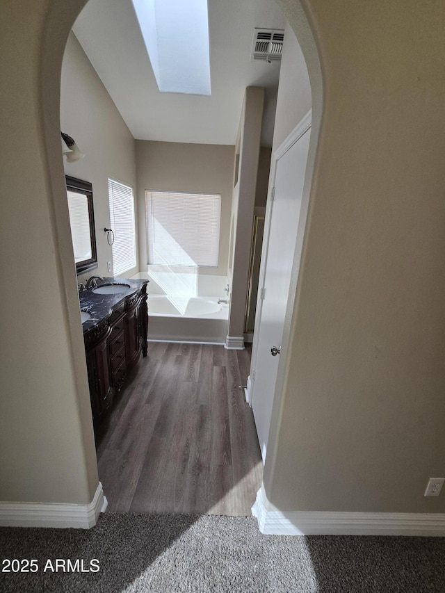 bathroom with vanity, a tub to relax in, and hardwood / wood-style floors