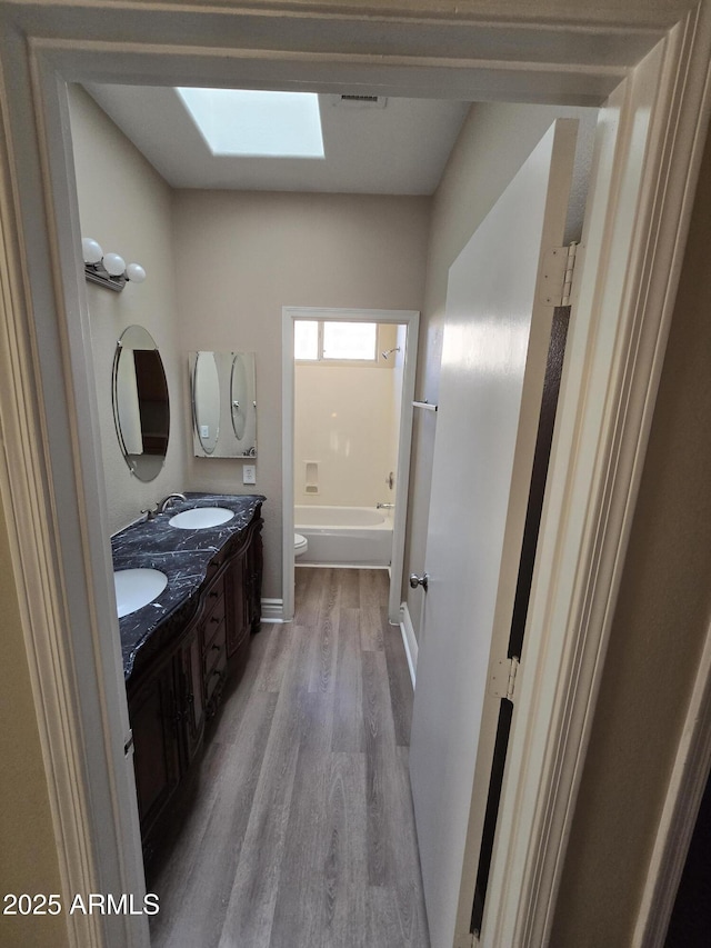 bathroom with vanity, toilet, hardwood / wood-style floors, and a skylight