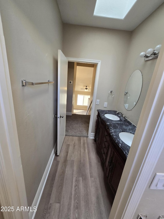 bathroom with vanity, hardwood / wood-style flooring, and a skylight