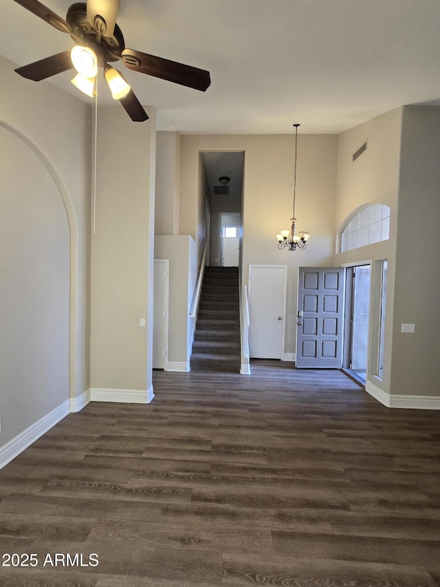 spare room with a towering ceiling, a chandelier, and dark hardwood / wood-style flooring