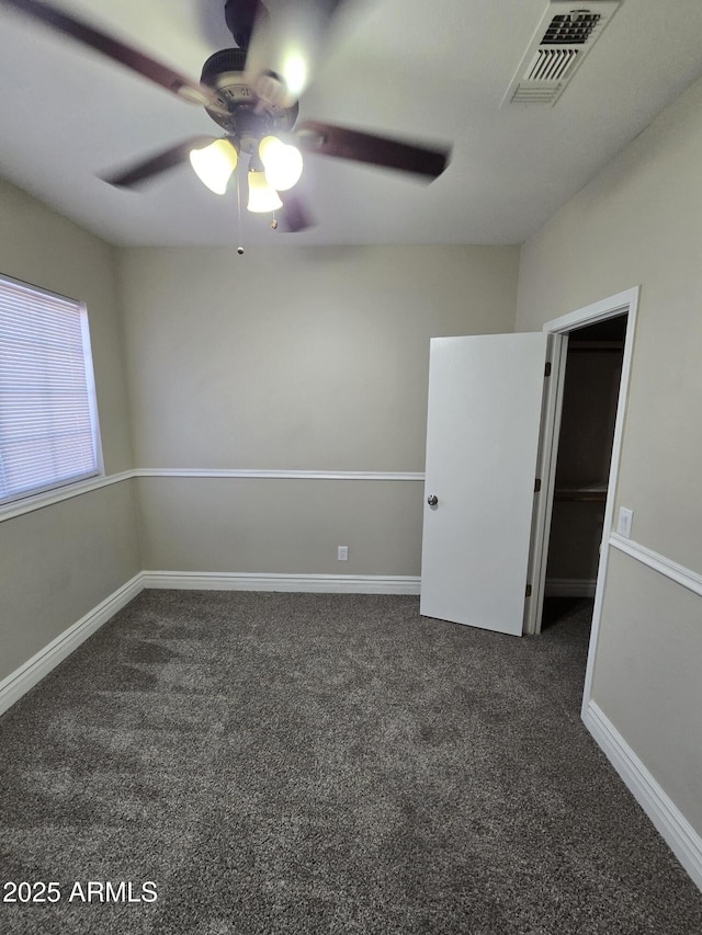 empty room with ceiling fan and dark carpet