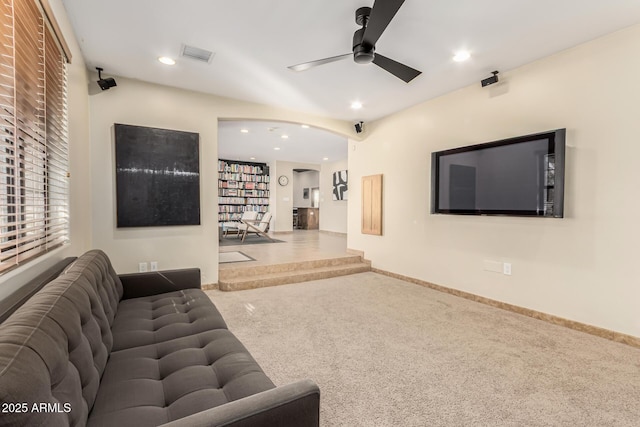 living area with carpet, arched walkways, visible vents, ceiling fan, and baseboards