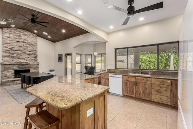 kitchen with a breakfast bar area, white dishwasher, a sink, a kitchen island, and hanging light fixtures