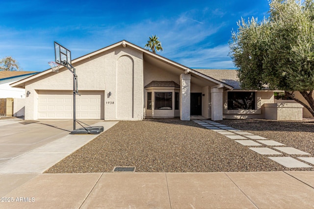 mid-century modern home with driveway, an attached garage, and stucco siding