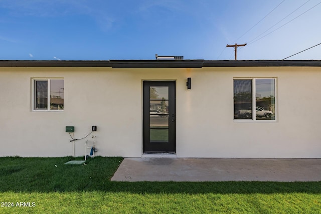 back of house with a patio and a lawn