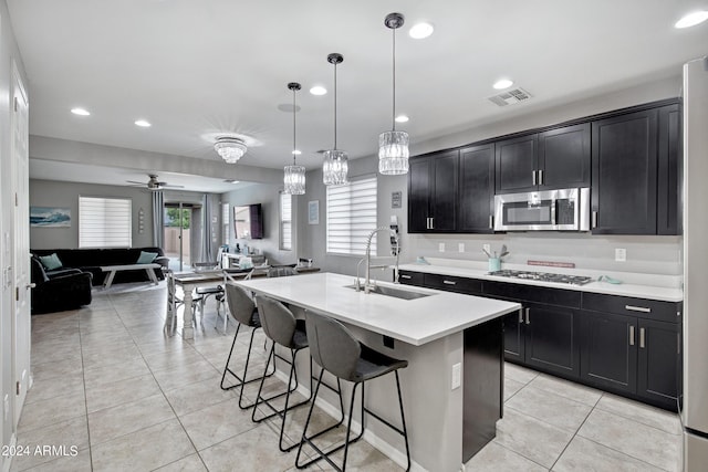 kitchen with stainless steel appliances, ceiling fan, sink, pendant lighting, and an island with sink