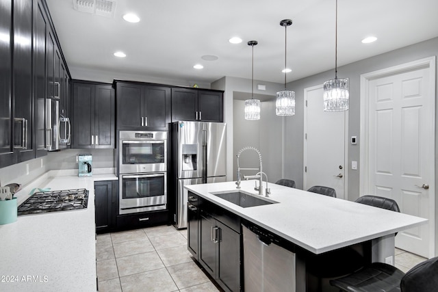 kitchen with sink, stainless steel appliances, an island with sink, pendant lighting, and a breakfast bar area