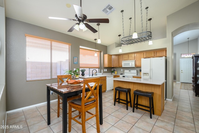 kitchen with sink, white appliances, light tile patterned floors, a kitchen island, and ceiling fan