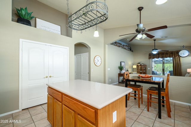 kitchen with a high ceiling, a kitchen island, and light tile patterned floors