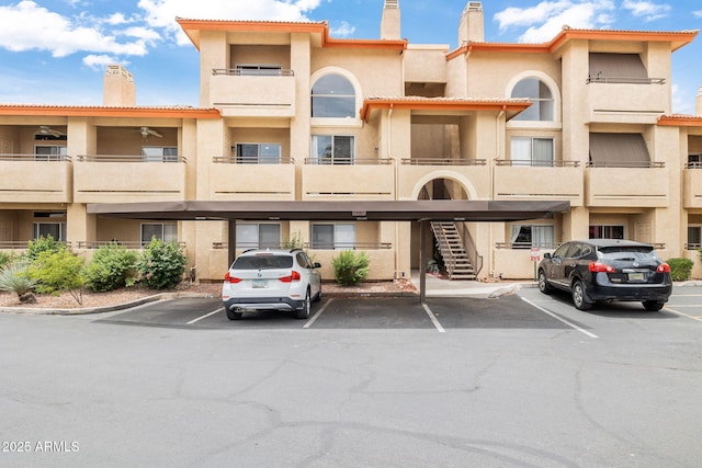 view of property featuring covered and uncovered parking and stairs