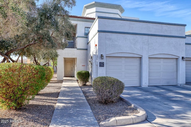 view of front facade with concrete driveway, an attached garage, a balcony, and stucco siding