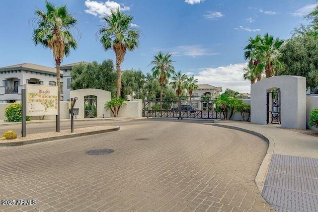 view of street with a gate, curbs, and a gated entry