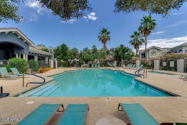 community pool with a patio and fence