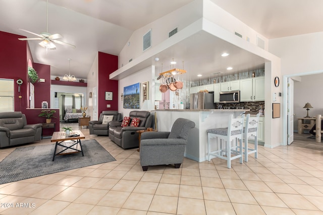 tiled living room with high vaulted ceiling and ceiling fan with notable chandelier