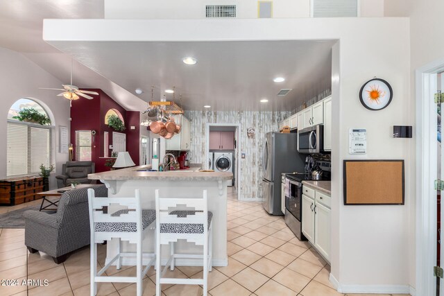 kitchen with appliances with stainless steel finishes, lofted ceiling, white cabinets, and a breakfast bar