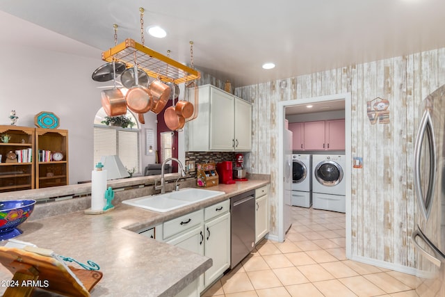 kitchen with washer and dryer, appliances with stainless steel finishes, sink, backsplash, and light tile patterned floors