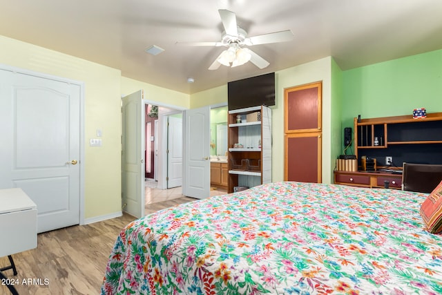 bedroom with light wood-type flooring, ceiling fan, and connected bathroom