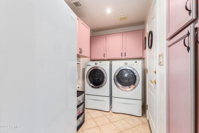 washroom with light tile patterned flooring, washing machine and clothes dryer, and cabinets