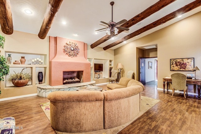 living room featuring ceiling fan, hardwood / wood-style flooring, a stone fireplace, and lofted ceiling with beams