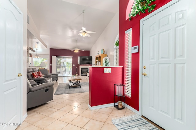 foyer entrance featuring ceiling fan, light tile patterned floors, and vaulted ceiling