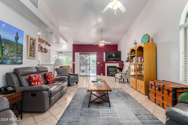 living room featuring ceiling fan, light tile patterned floors, vaulted ceiling, and a fireplace