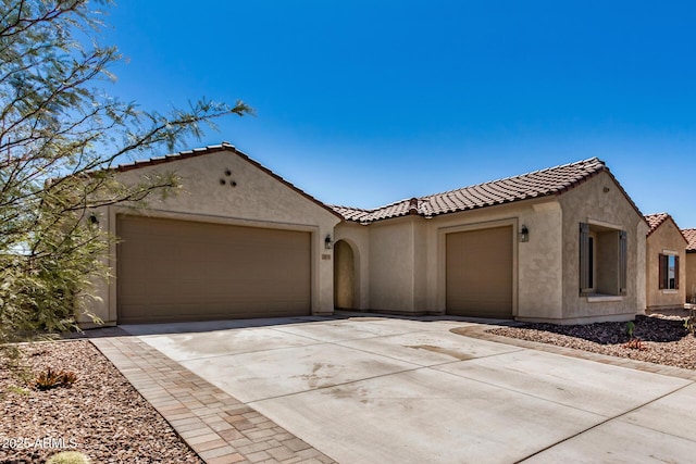 mediterranean / spanish house with concrete driveway, a tiled roof, an attached garage, and stucco siding