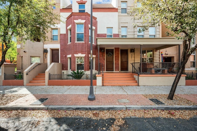 multi unit property with stucco siding, brick siding, and covered porch