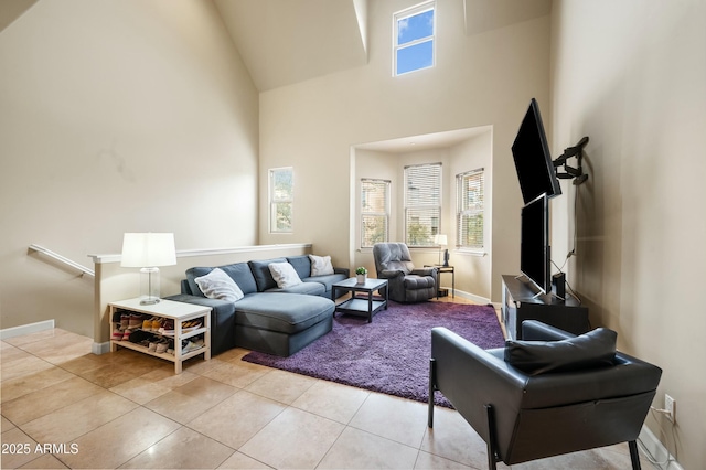 living room with baseboards, high vaulted ceiling, and light tile patterned flooring