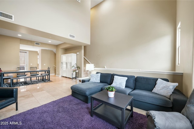 living area with visible vents, a high ceiling, and light tile patterned flooring