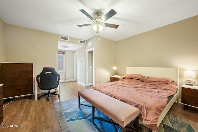 bedroom featuring visible vents, a ceiling fan, baseboards, and wood finished floors