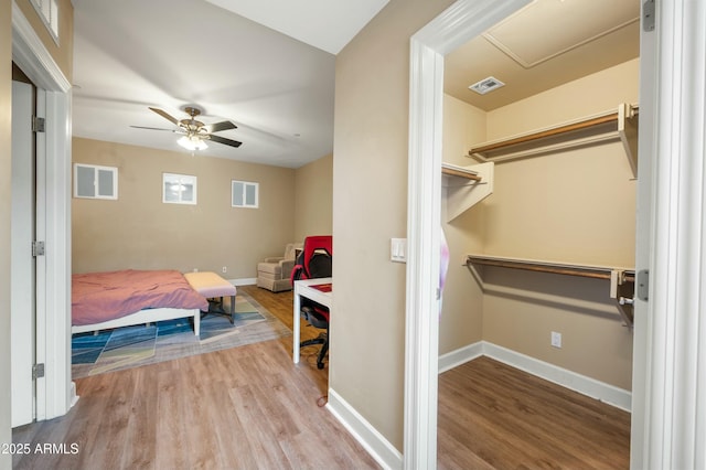 bedroom featuring ceiling fan, wood finished floors, visible vents, and baseboards