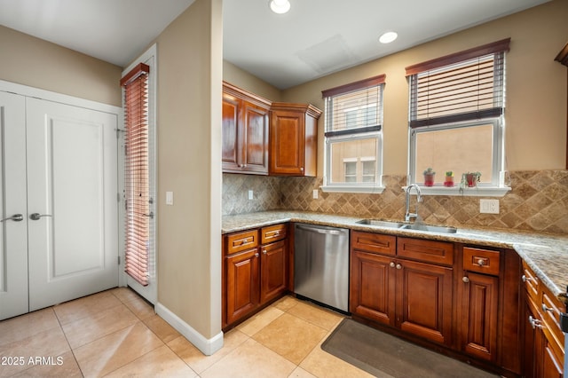 kitchen with brown cabinets, a sink, tasteful backsplash, light tile patterned flooring, and dishwasher