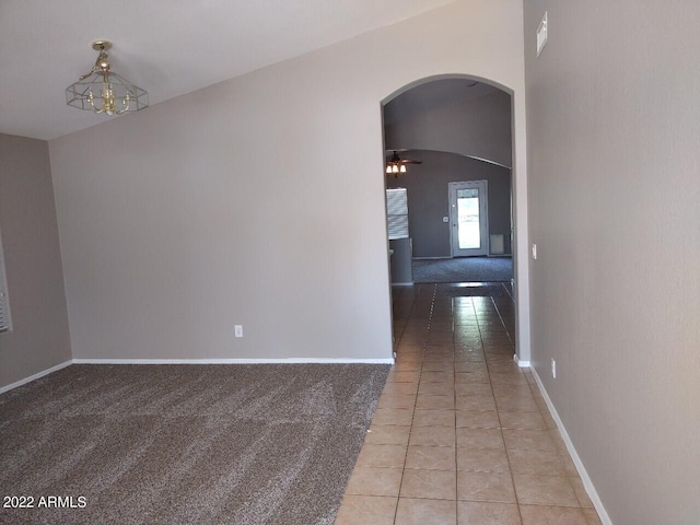 hallway featuring vaulted ceiling, a notable chandelier, and light tile patterned flooring