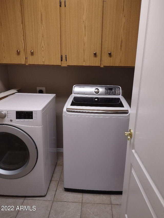 laundry area with washer and clothes dryer, cabinets, and light tile patterned floors