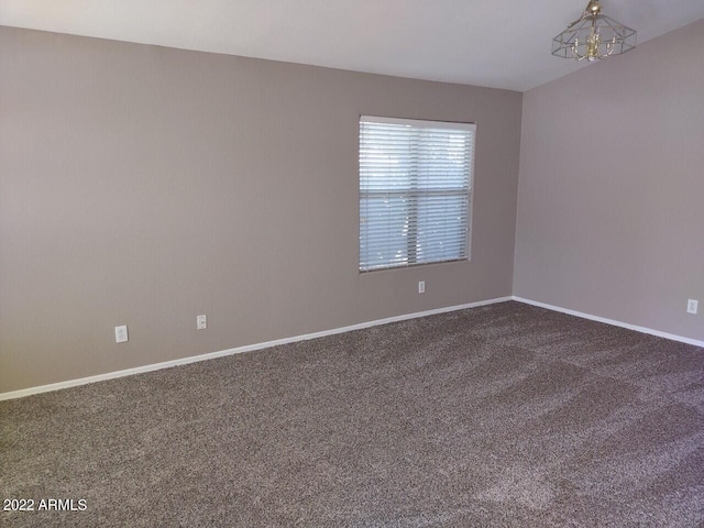 empty room featuring carpet flooring and an inviting chandelier