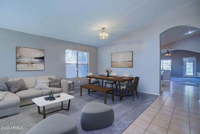 living room with ceiling fan with notable chandelier, light tile patterned floors, and vaulted ceiling