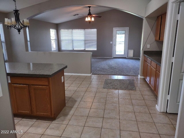 kitchen featuring ceiling fan with notable chandelier, light tile patterned floors, pendant lighting, and vaulted ceiling