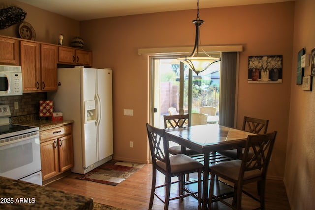 kitchen with backsplash, hardwood / wood-style floors, decorative light fixtures, and white appliances