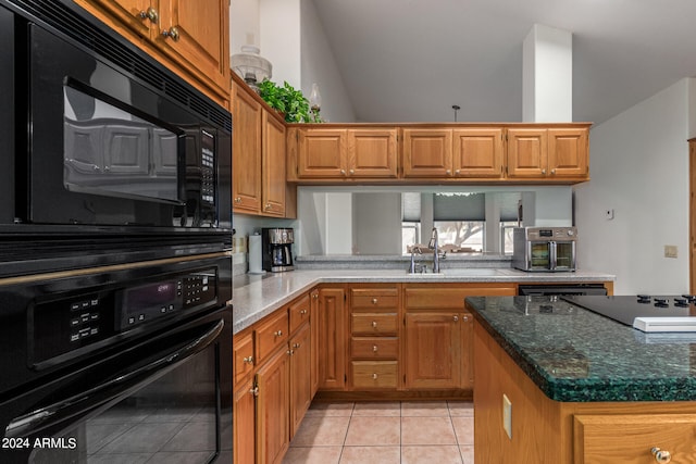 kitchen featuring dark stone countertops, vaulted ceiling, sink, black appliances, and light tile patterned flooring