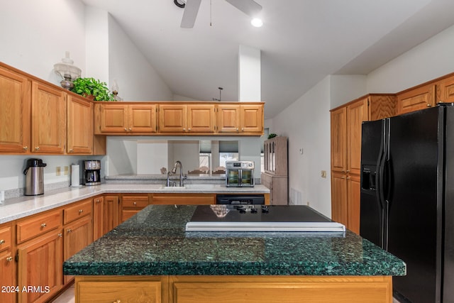 kitchen with a kitchen island, vaulted ceiling, dark stone countertops, ceiling fan, and black fridge