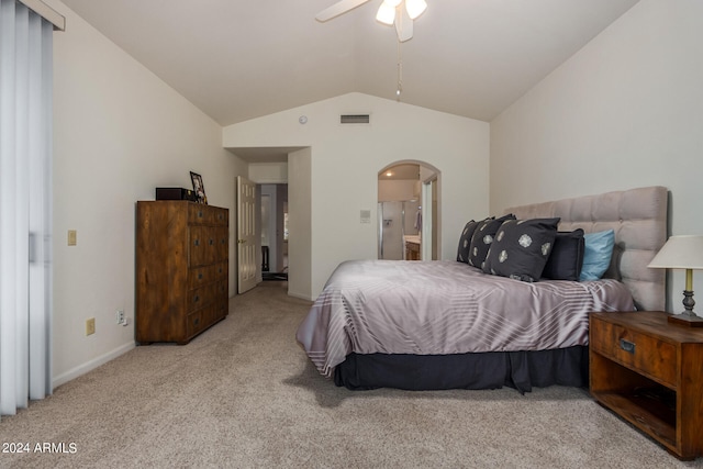 bedroom featuring ceiling fan, light colored carpet, vaulted ceiling, and ensuite bath