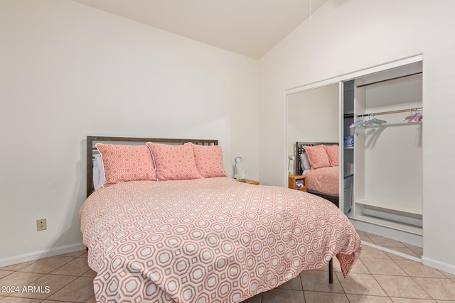 bedroom featuring light tile patterned floors, vaulted ceiling, and a closet