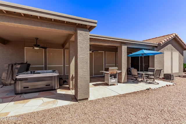 back of house featuring ceiling fan, a patio area, and a hot tub