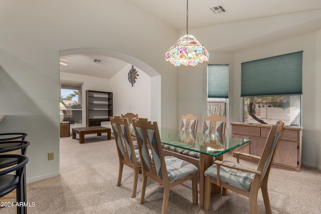 dining area featuring vaulted ceiling and light colored carpet