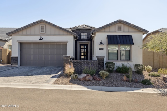 view of front of house with a garage, decorative driveway, a tile roof, and board and batten siding